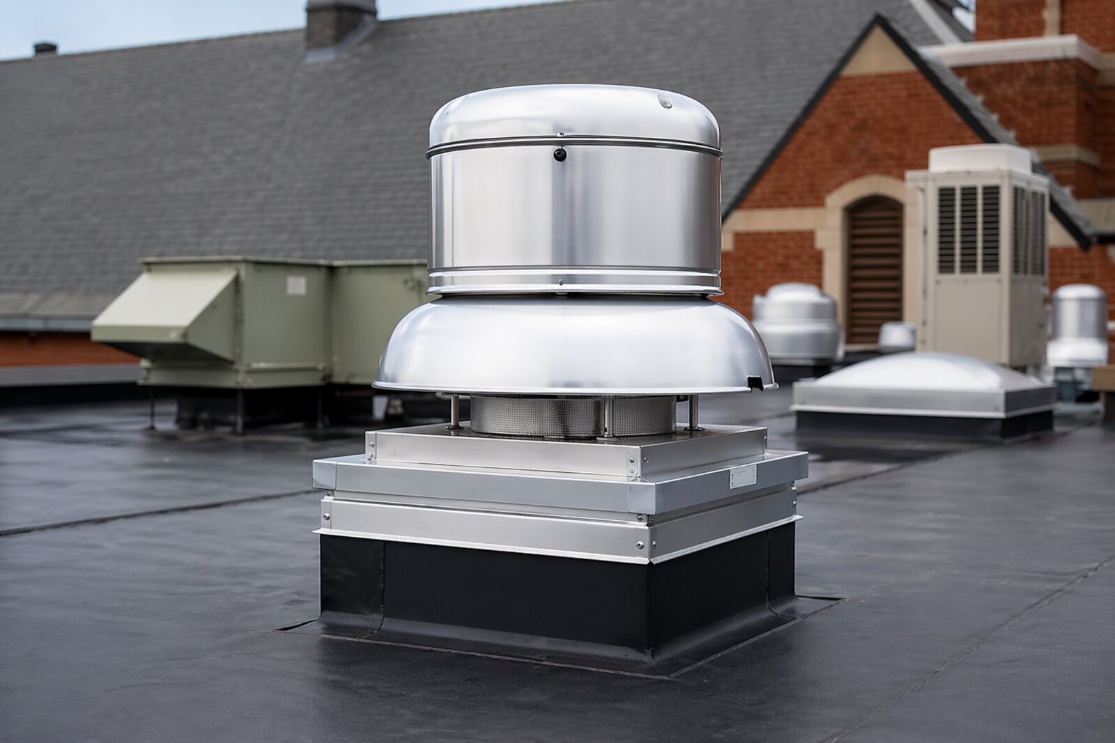 New stainless rooftop exhaust fan installed and curbed on a flat membrane roof